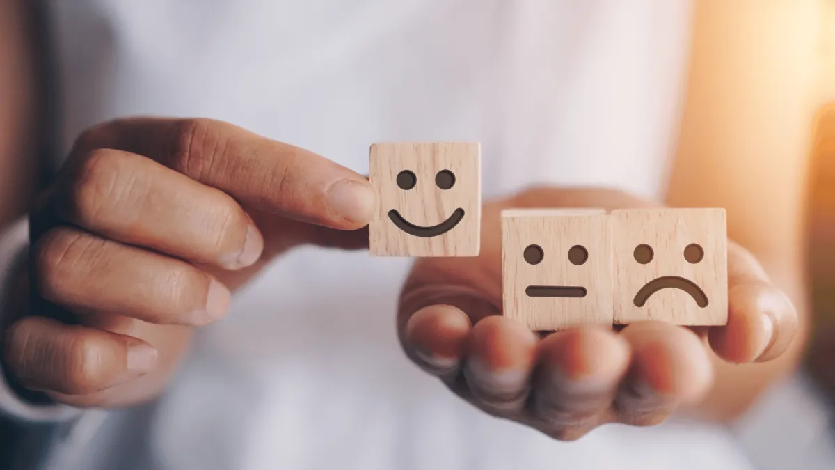 Person's Hands Holding Wooden Cubes with Various Emotions