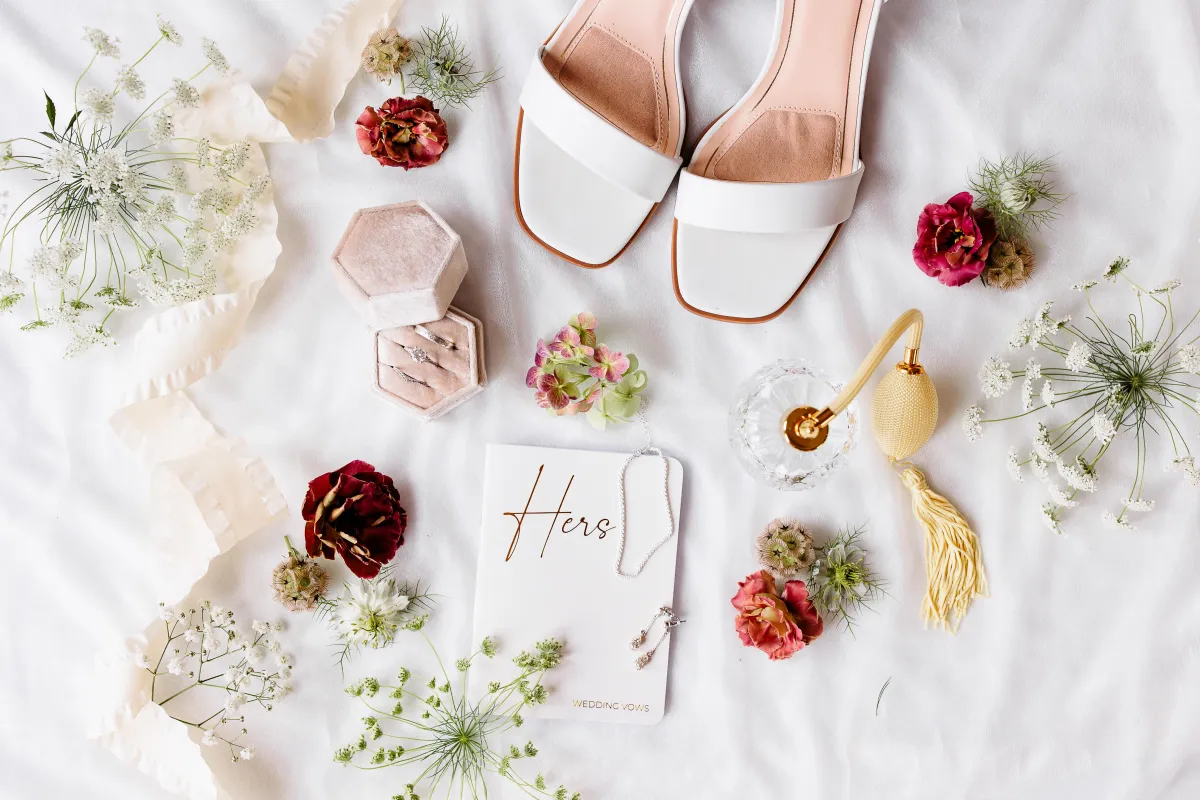 Flat lay of wedding details including vows, shoes, and flowers, photographed by Double Knot Photography, showcasing stylish bridal accessories at Sabrina Cedars in Abilene Texas