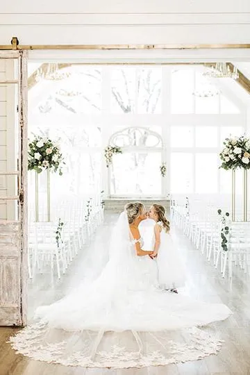 Elegant bride sharing an intimate moment with the flower girl filled with emotion and love at French Farmhouse
