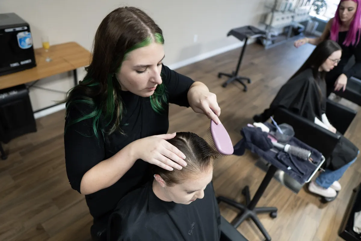 Emily Keoppen Checking clients hair for hair loss.