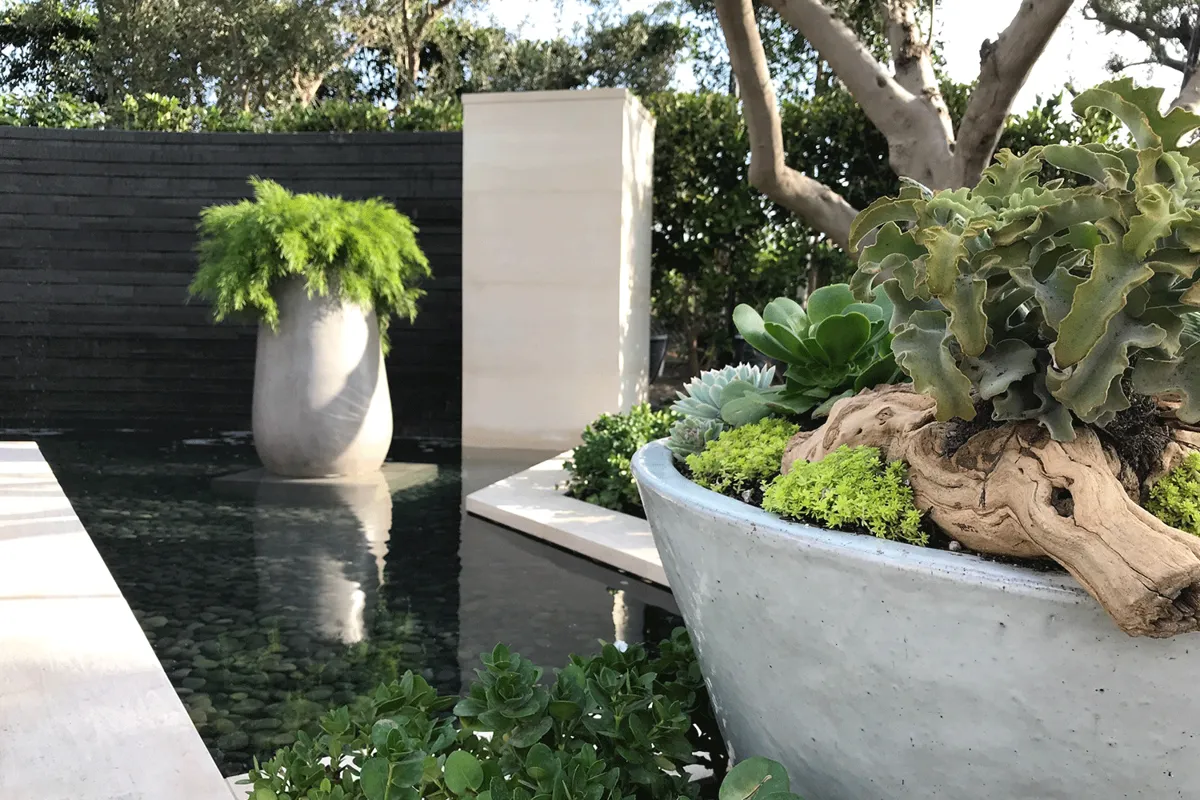 Modern stone water feature with succulent planter in luxury landscape.