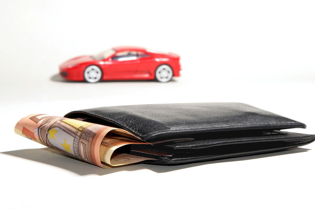 Wallet with cash in foreground and toy car in background