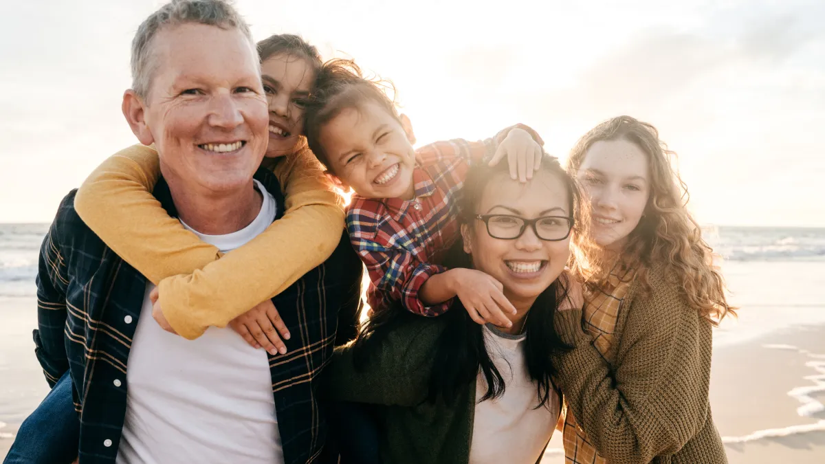 Smiling blended family on a beach. Parents and two children close together. Image for article on blended family estate planning, trusts, beneficiary updates, and protecting heirs.
