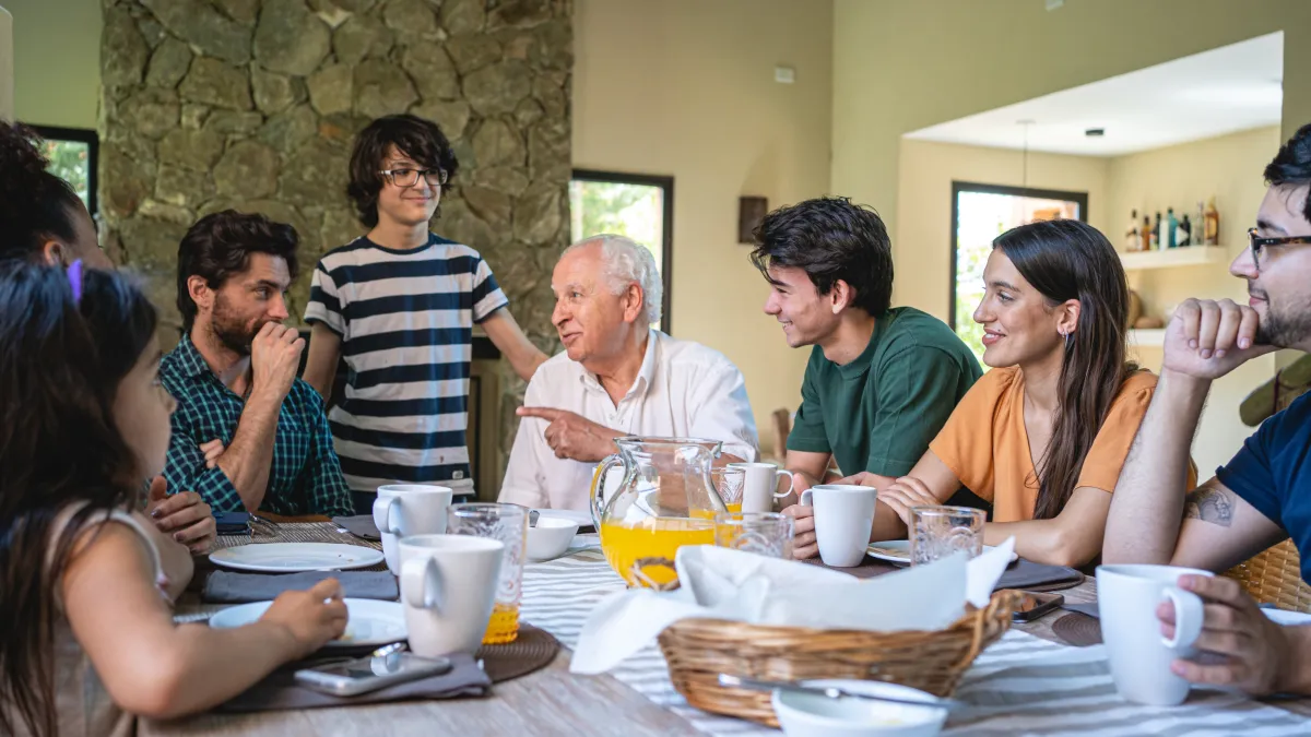A family gathered around a dining table sharing a warm conversation about estate planning and legacy decisions in a calm and positive setting.