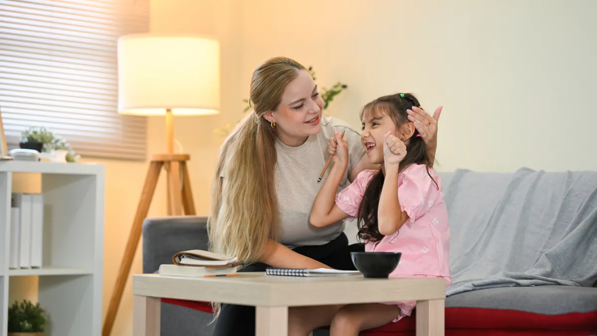 Single mother sitting with her young daughter at home, reviewing notes together and sharing a warm moment, representing estate planning decisions, guardianship planning, and protecting a child’s future