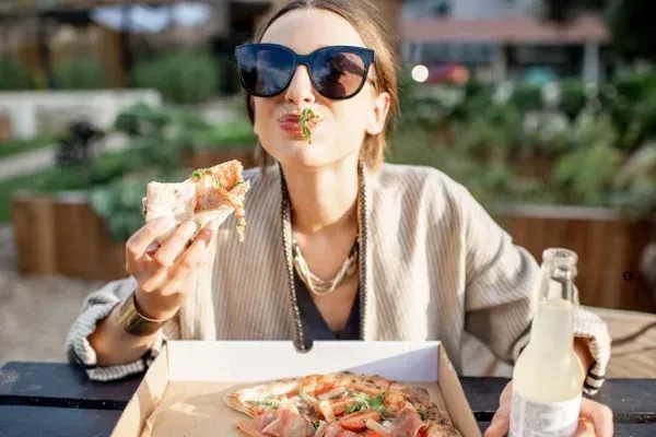 Mujer comiendo; concepto de intolerancia alimentaria con síntomas digestivos, fatiga y piel reactiva.