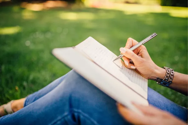 A person writing in a journal, representing the process of tracking emotional triggers and gaining self-awareness.