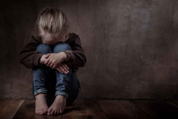 Sad little girl sitting on the floor, representing an inner child at the root on an anxious attachment type