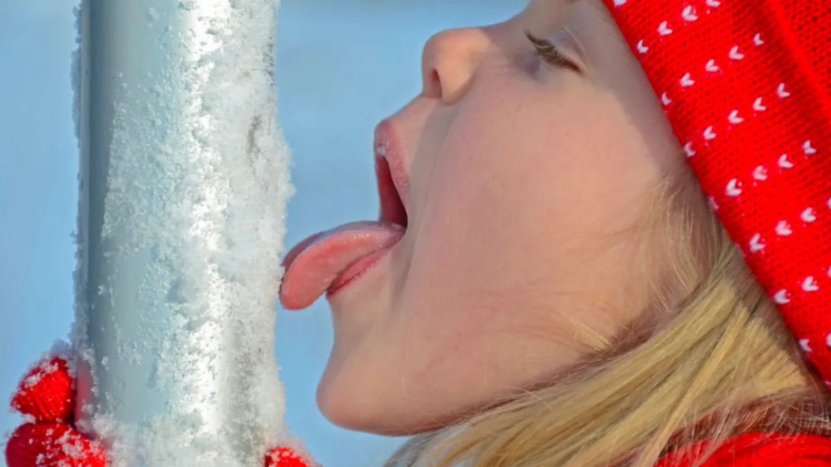 girl with tongue on frozen pole