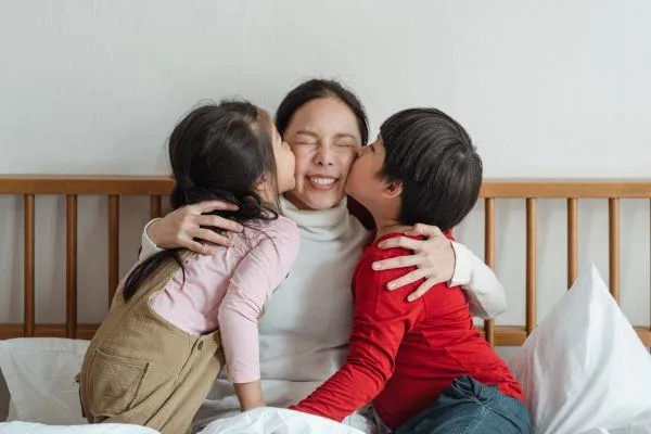 Mom getting love from her two kids, happy as a parent
