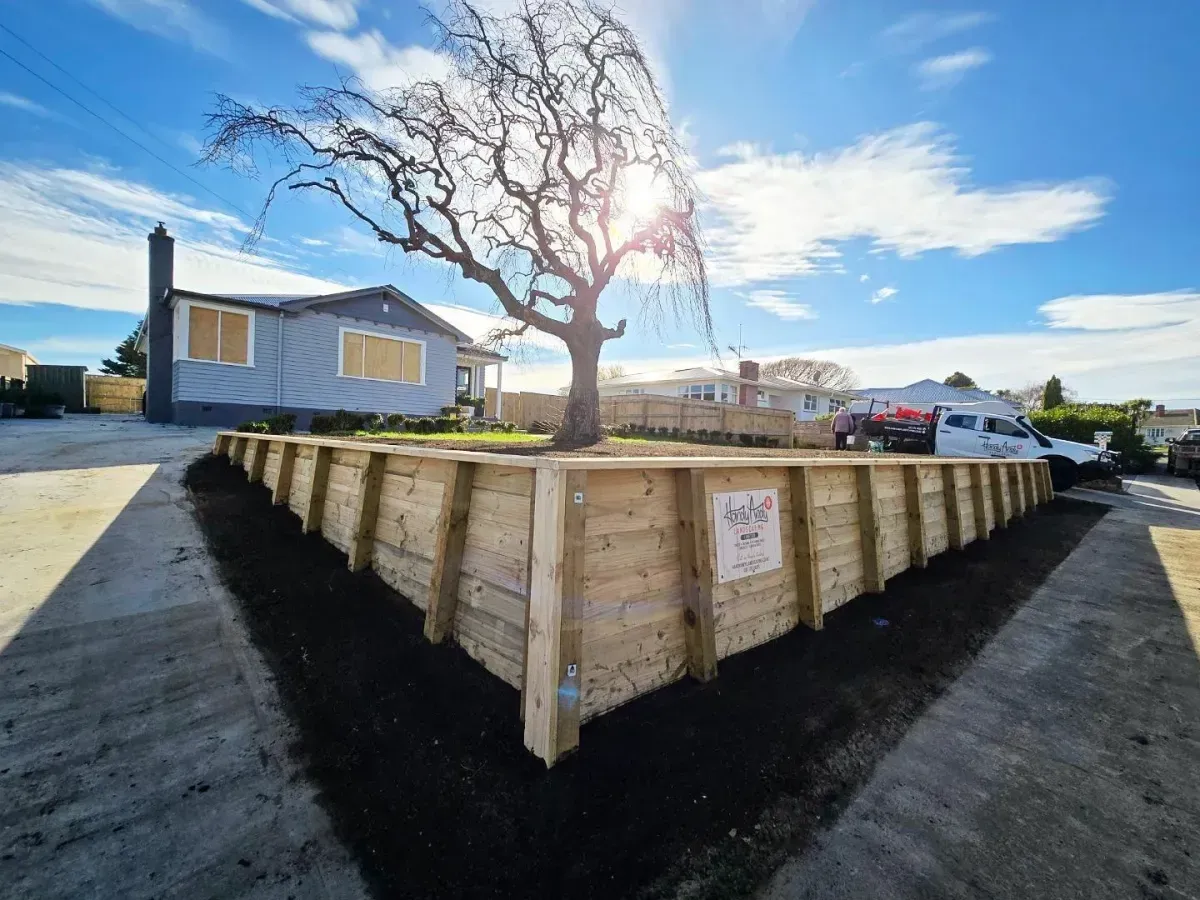 Timber retaining wall on a landscaped Whanganui property, offering erosion control and natural aesthetic appeal