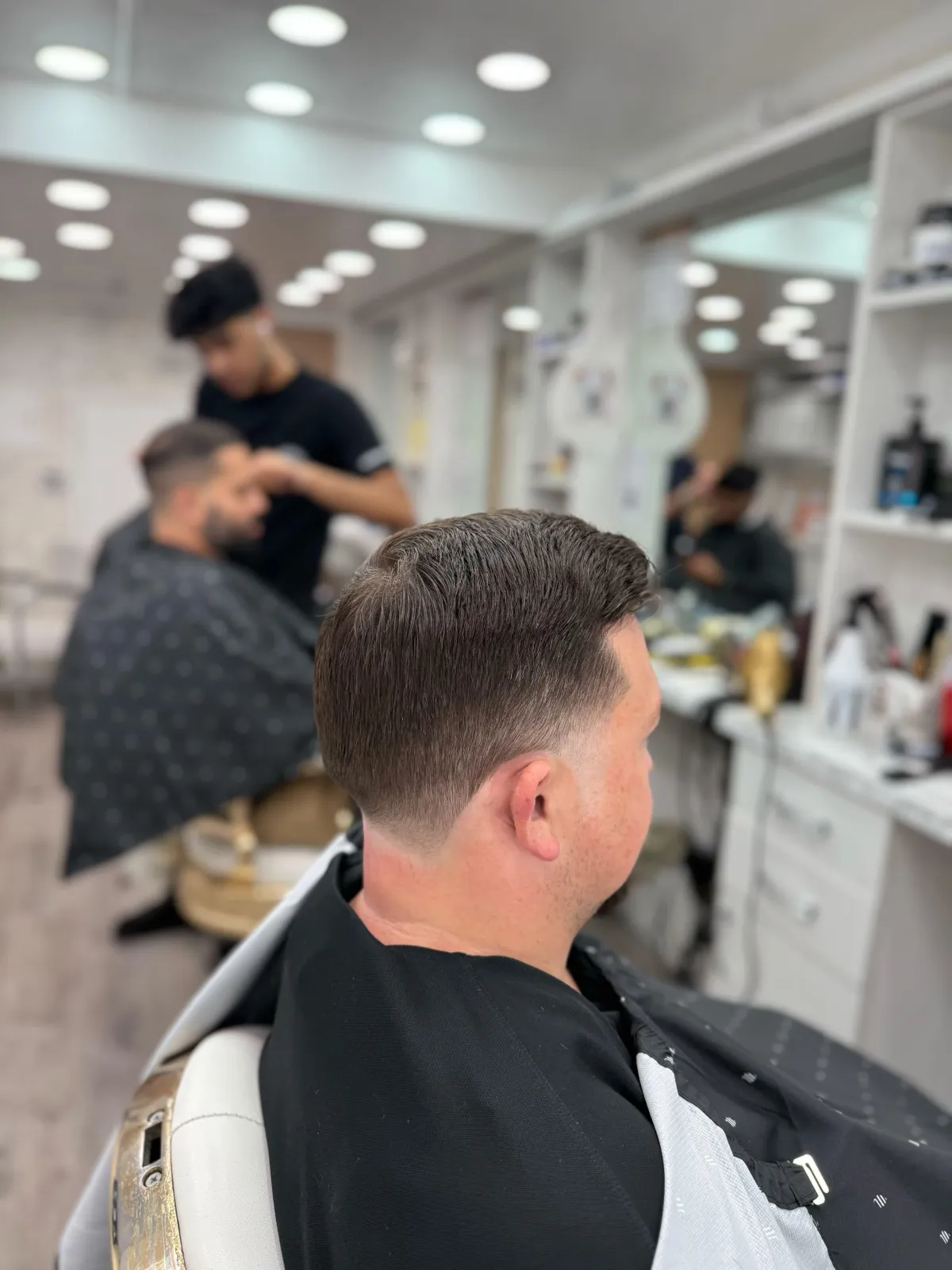 Barber at Imperial Barbershop NYC giving a modern fade with classic straight razor finish