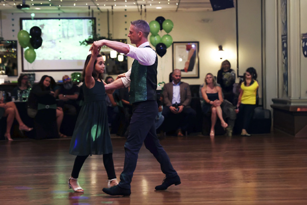 Dance instructor with youth dancing at charity event in ballroom