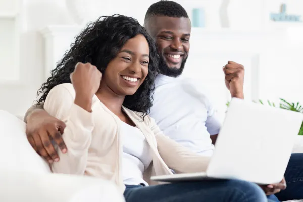 happy couple looking at laptop celebrating