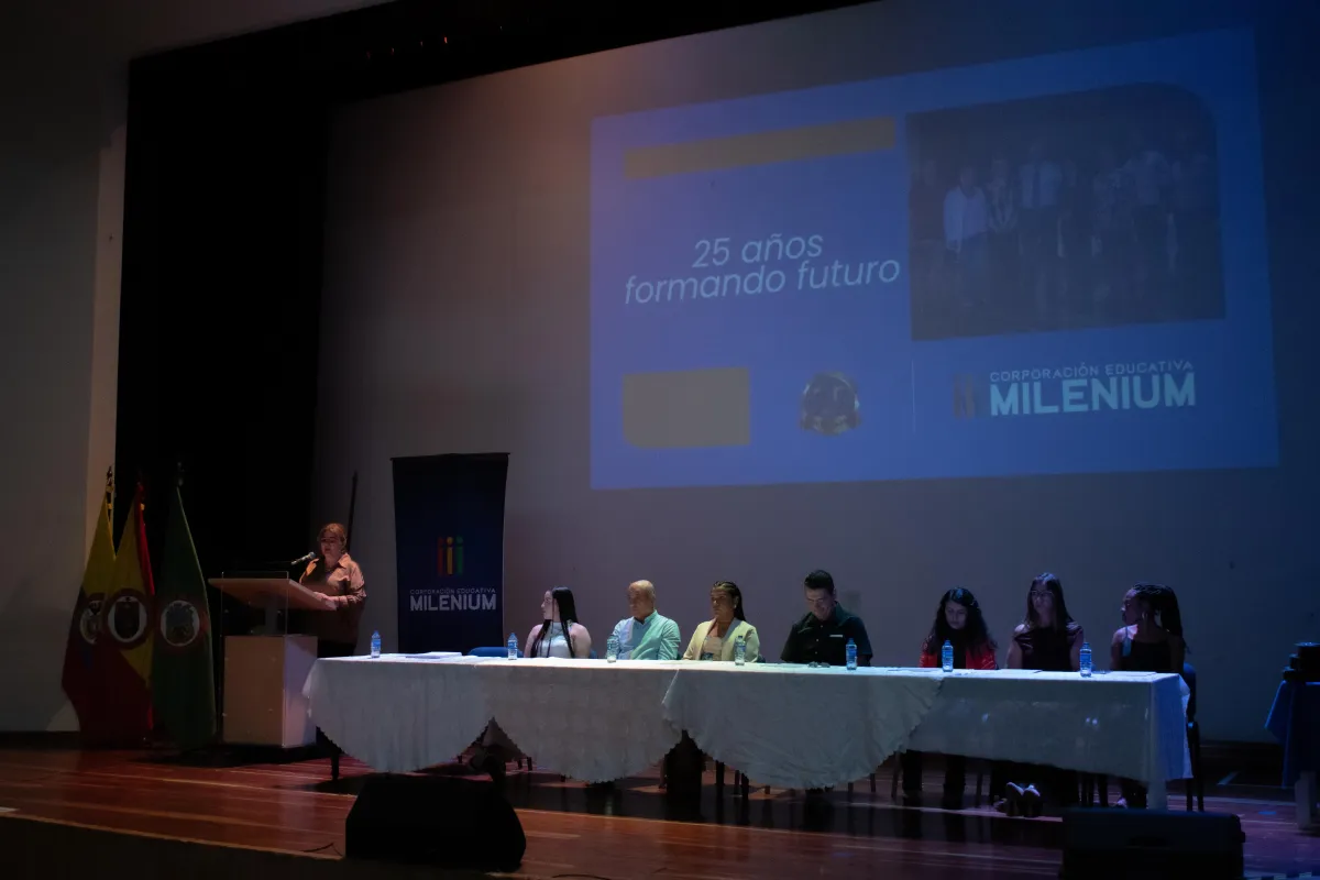 Celebración de los 25 años de la Corporación Educativa Milenium en Pereira, con directivos en tarima y la proyección del lema “25 años formando futuro”.