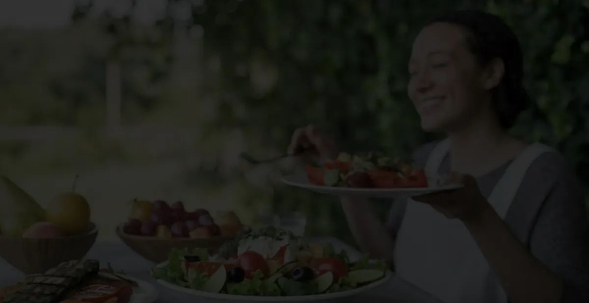 A smiling individual enjoying a fresh, colorful salad outdoors, promoting healthy eating and wellness.