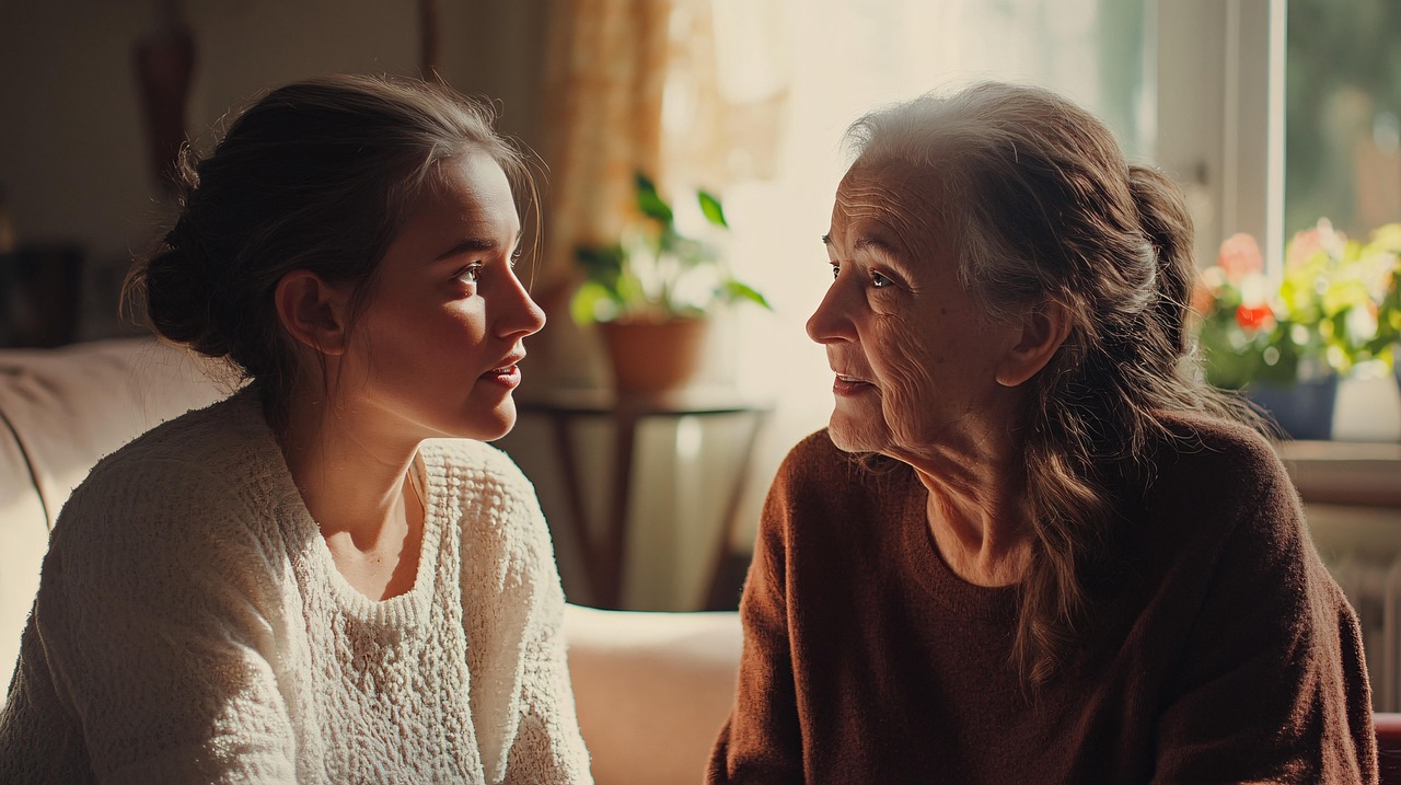 Adult daughter gently talks to aging mother at home, trying to introduce the idea of help