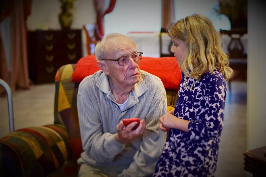 A caring adult child helps an older parent pack a memory-filled home, symbolizing the emotional and practical journey of senior transitions.