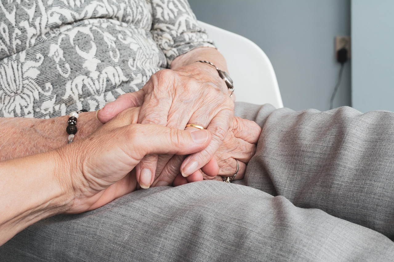 An adult daughter gently holds her mother’s hand in a quiet living room, capturing the emotional reality of rapid dementia decline and urgent caregiving decisions.