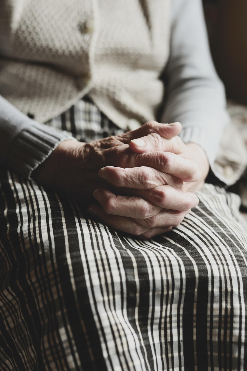 Elderly man sitting with adult daughter, looking concerned as they discuss memory lapses at home