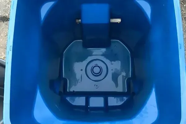 Freshly cleaned interior of a blue residential trash bin with a spotless, disinfected bin bottom.