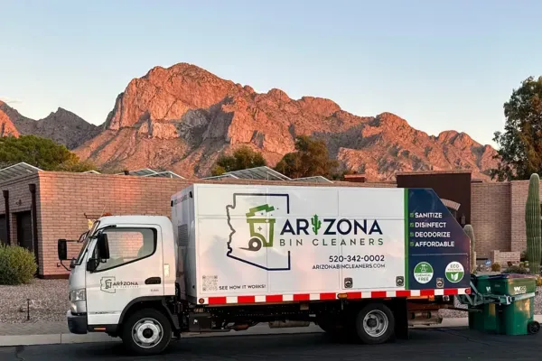 Arizona Bin Cleaners truck servicing curbside trash bins with scenic mountain backdrop at sunset.