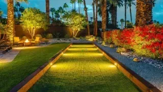 A serene backyard featuring a lush lawn, palm trees, and a well-maintained bocce ball court for leisure activities.