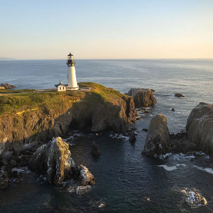 Outdoor seating at Rogue Spirits Sunset Bar in Newport, Oregon, overlooking Yaquina Bay Marina, offering handcrafted cocktails, Rogue ales, and coastal views.