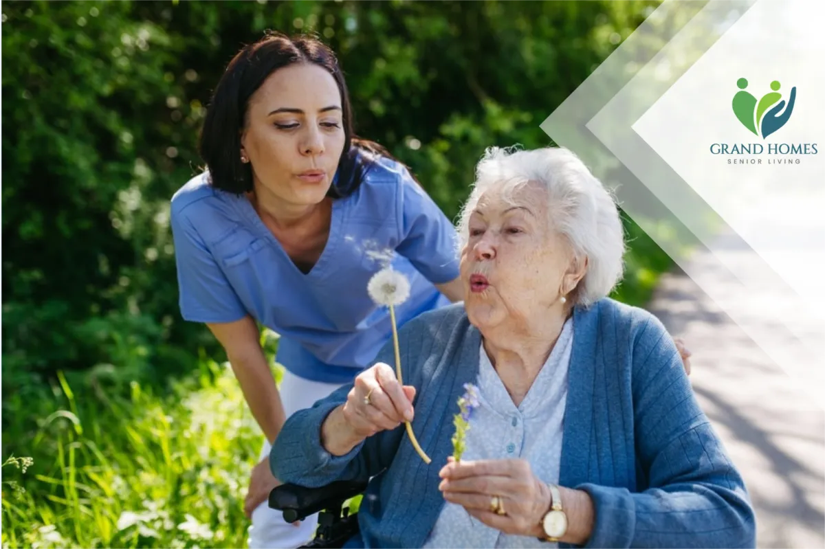 Caregiver and elderly woman blowing dandelions together outdoors, symbolizing compassionate senior care and quality of life.