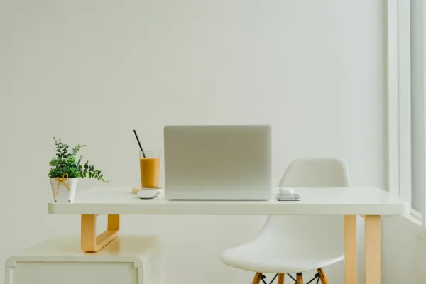 desk by window with laptop and iced coffee sat on top