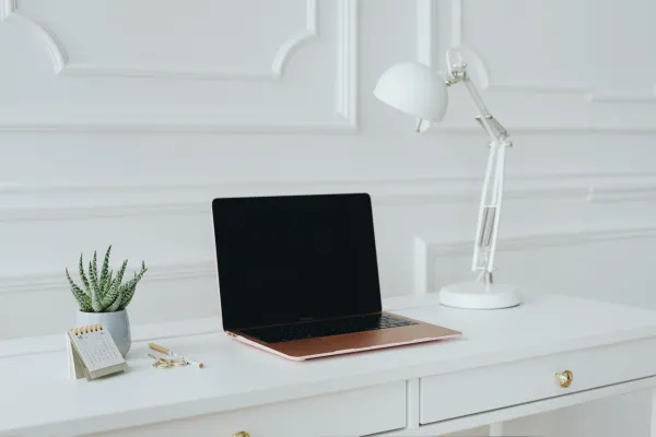 desk with a computer, lamp, and plant set on top of it.
