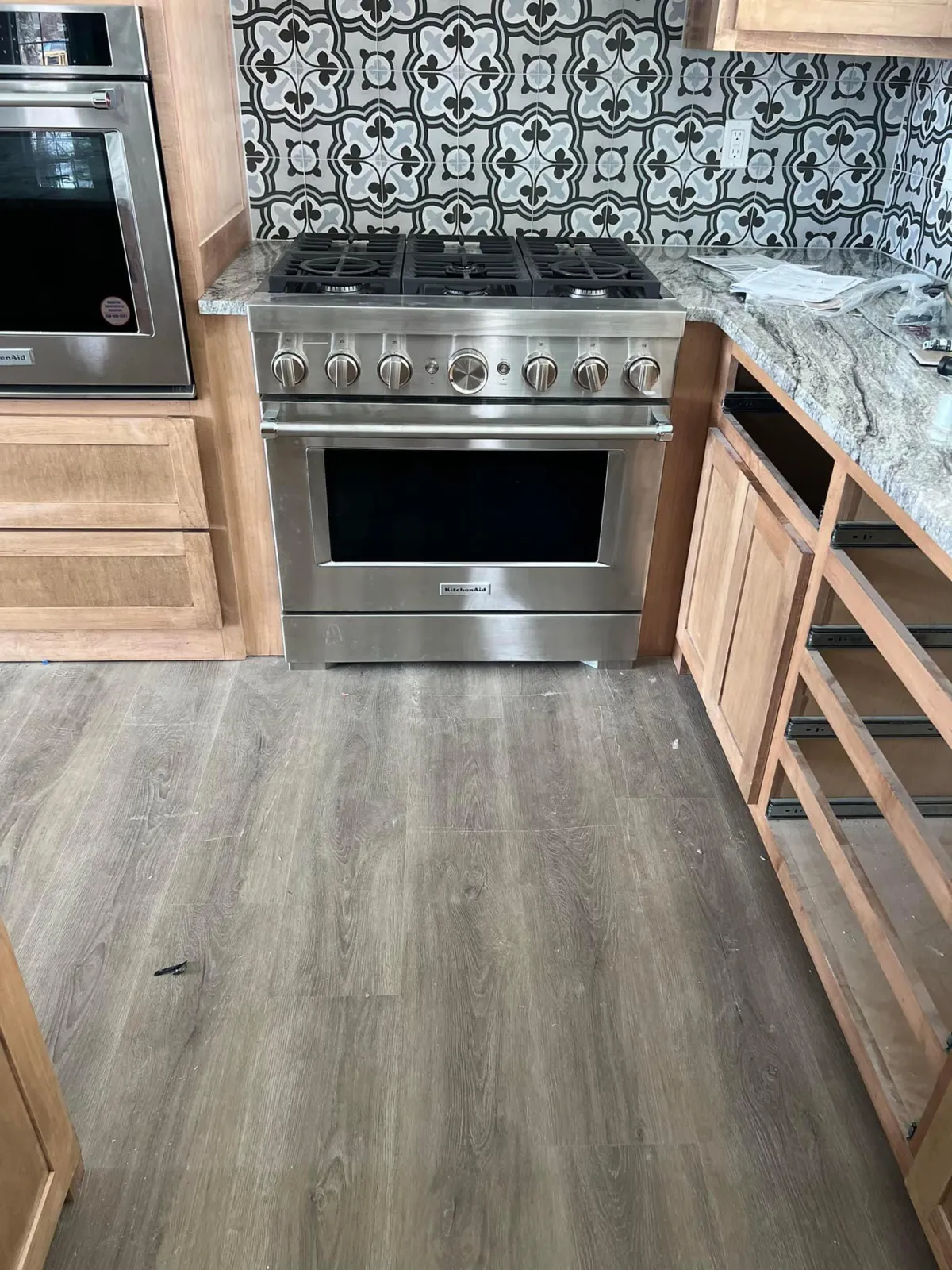"Contemporary kitchen featuring textured stone tile flooring, stainless steel appliances, and wooden cabinetry."