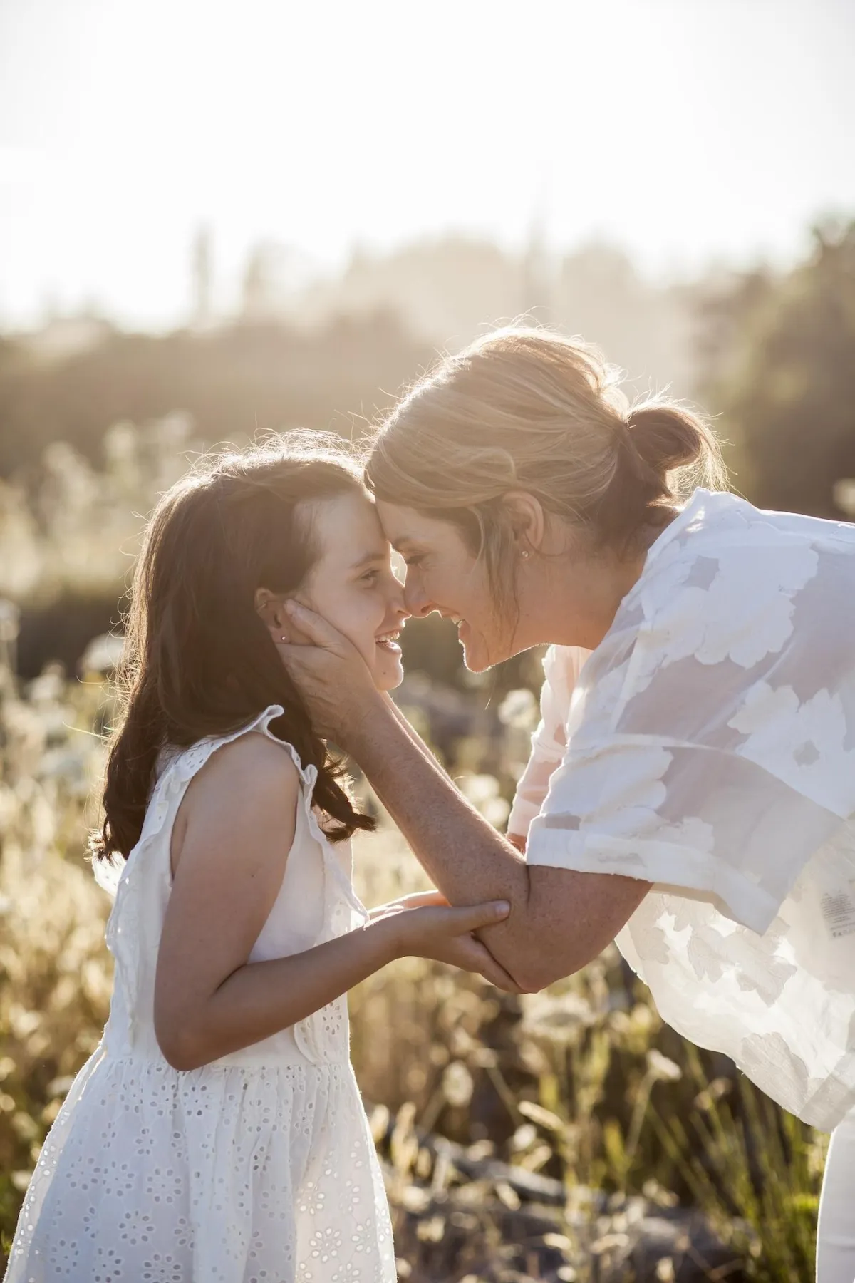 Mother and daughter touching noses in evening glow at Island View Beach
