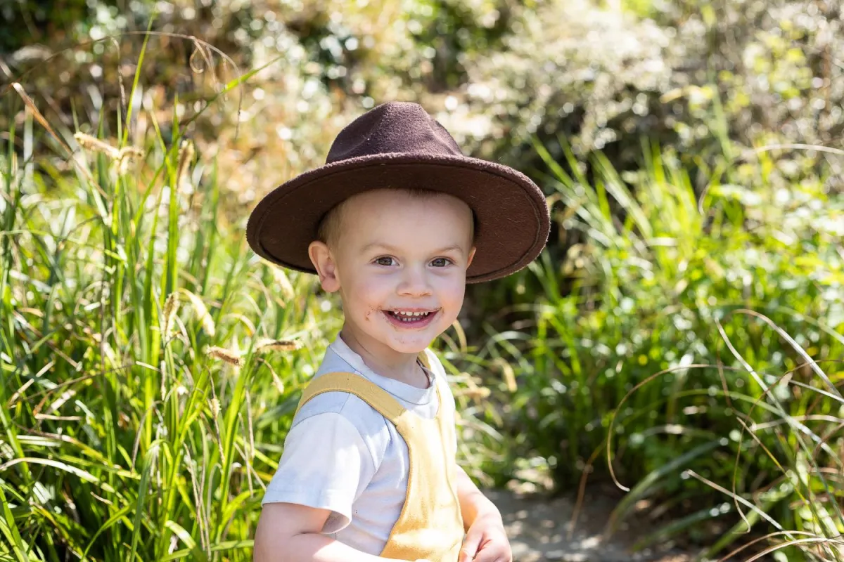 Little boy in backyard smiling at camera