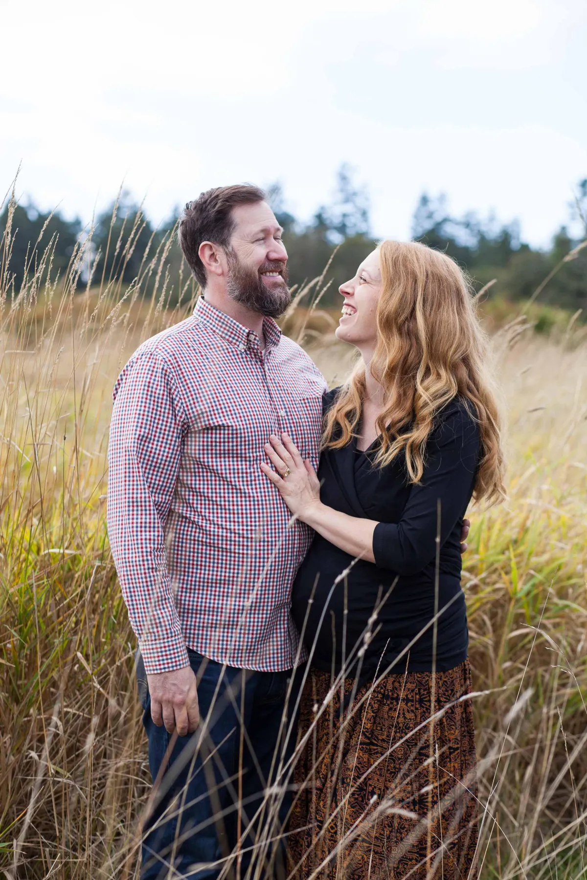 Maternity photo - Couple standing in field at Elk Lake Park