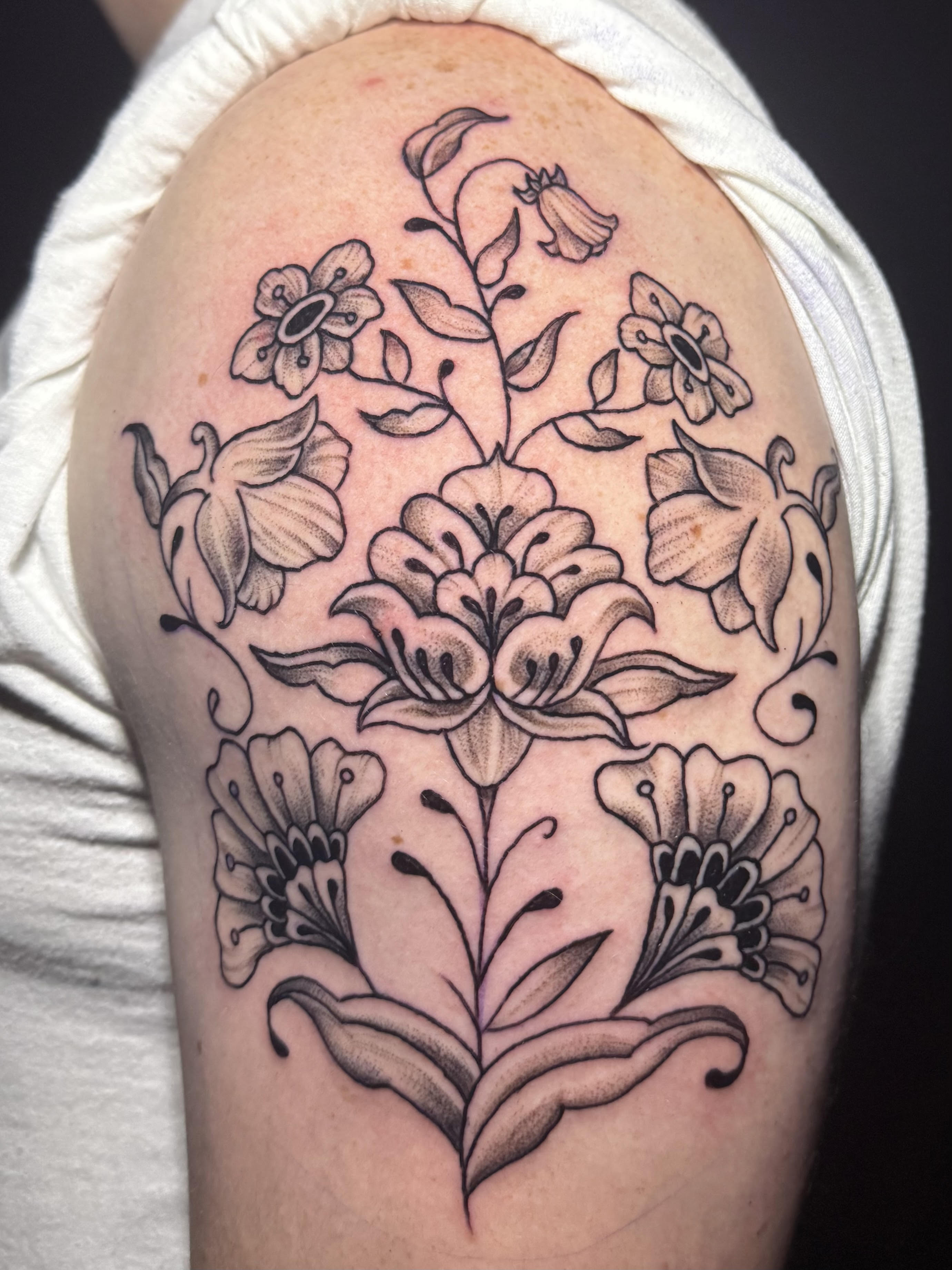 Photo of client's shoulder with an American traditional floral tattoo by Aiden at Red Arbor Tattoo