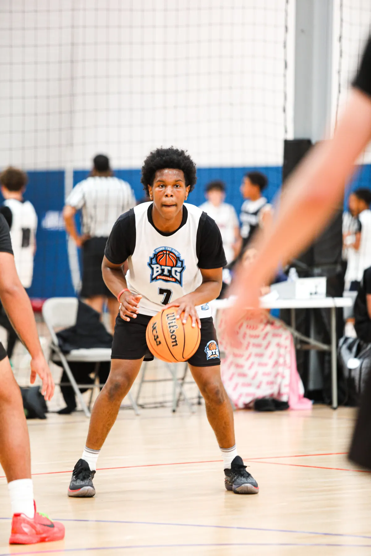 High school boy practicing a basketball dribbling drill in an indoor court