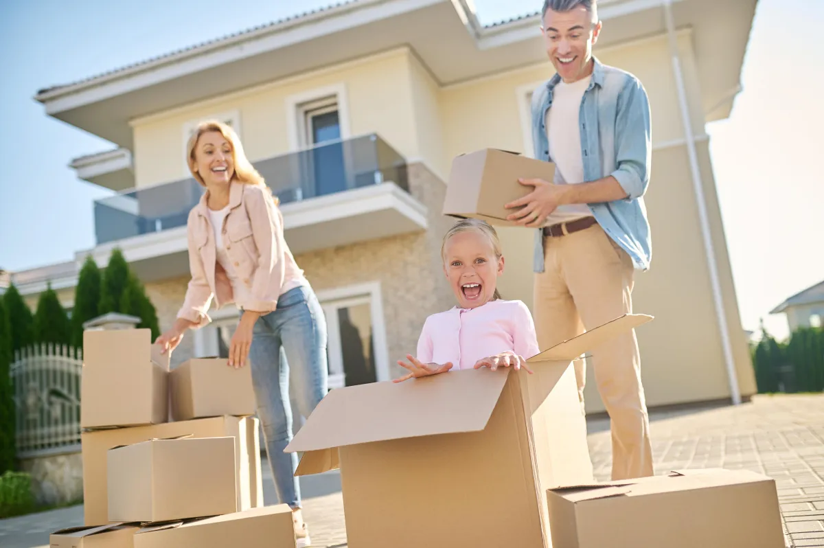 A Dallas family moving boxes into a new construction home under blue Texas skies.