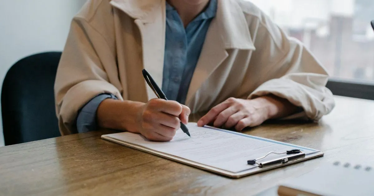 Person filling out paperwork on a clipboard at a desk, representing the process of completing OSHA 300 logs for workplace injury and illness recordkeeping compliance.