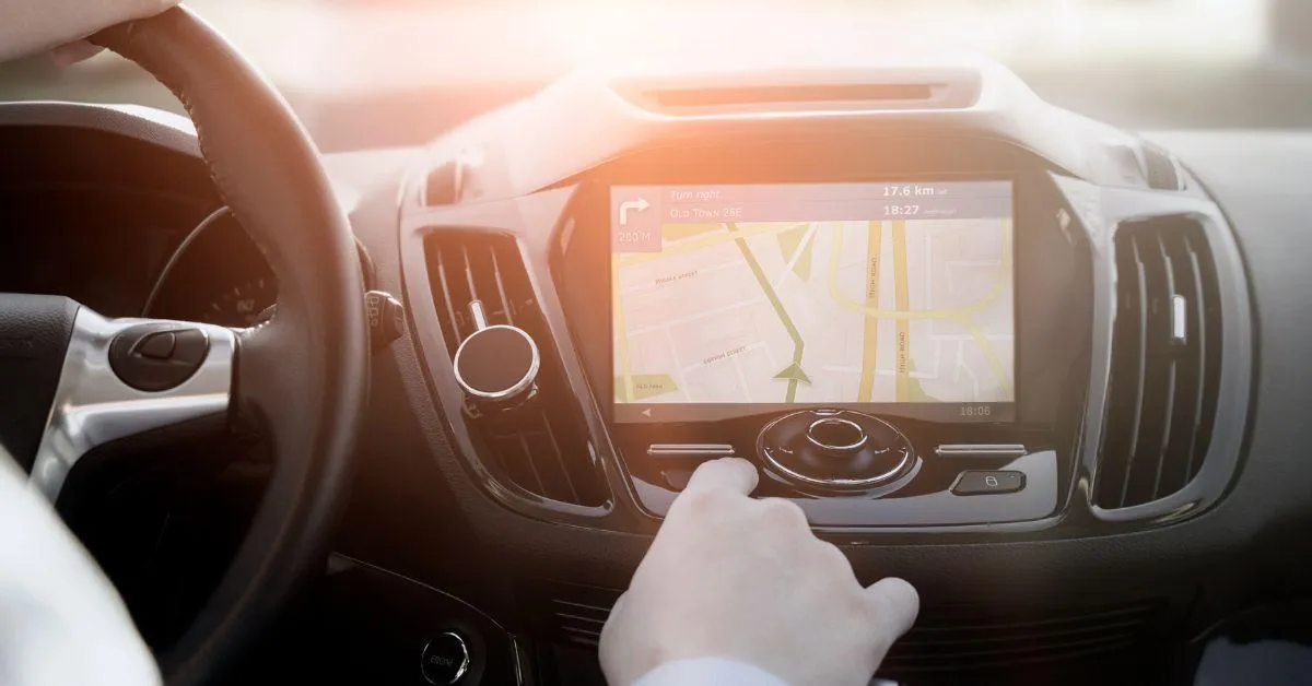Business driver using an in-car GPS navigation system with a touchscreen display showing a map and route directions.