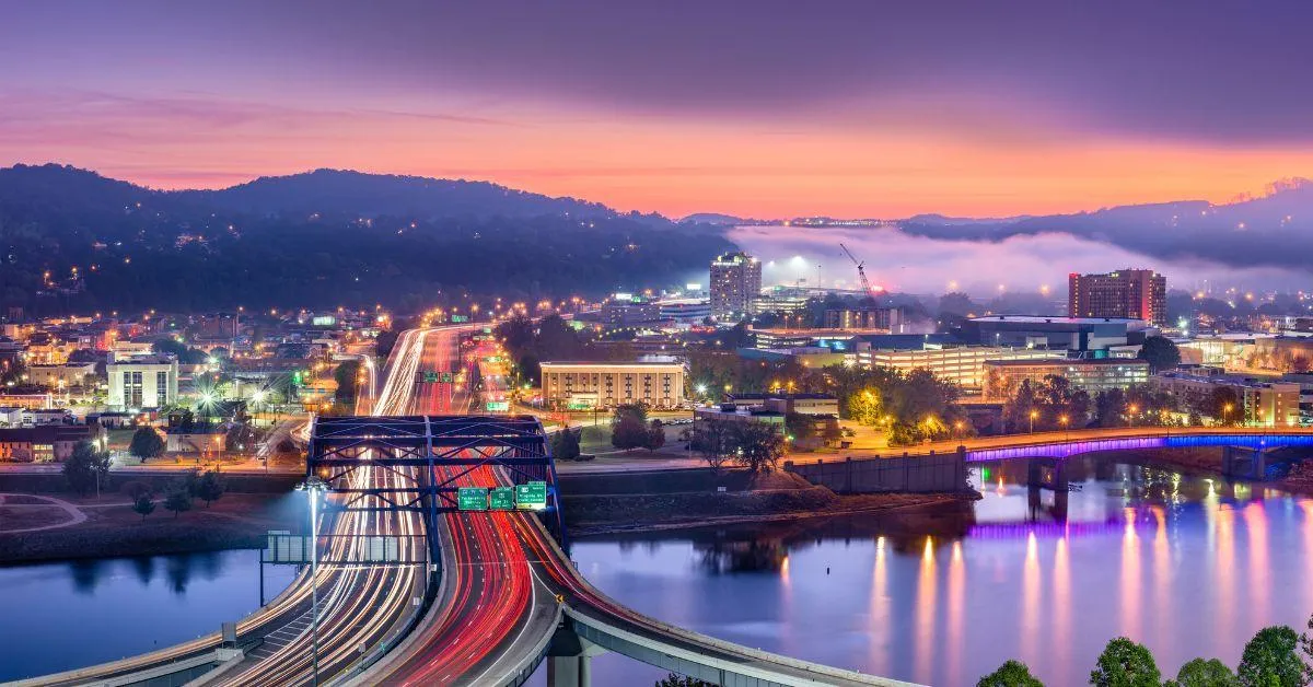 Scenic view of Charleston, West Virginia at dusk with illuminated highways and city buildings, representing the regulatory landscape that businesses in the state may face from government inspections.