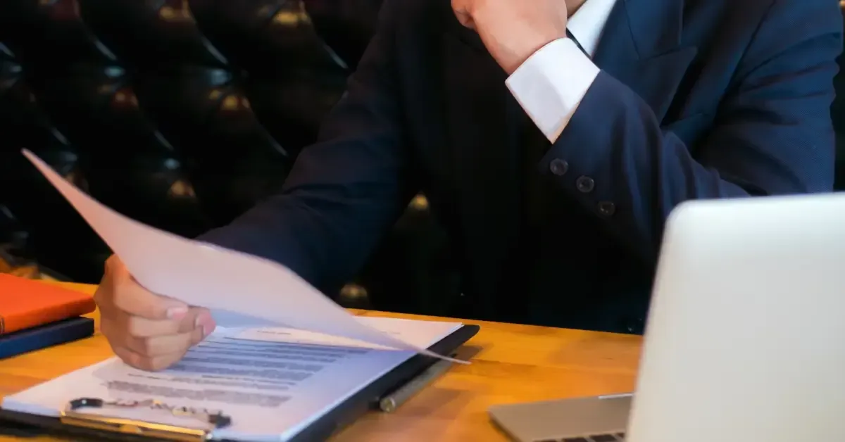 Business professional reviewing OSHA inspection documents at a desk with a laptop and clipboard.