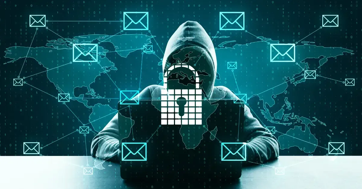 A hooded hacker sits at a laptop surrounded by digital icons of email envelopes and a glowing lock symbol, representing global ransomware and cybersecurity threats.