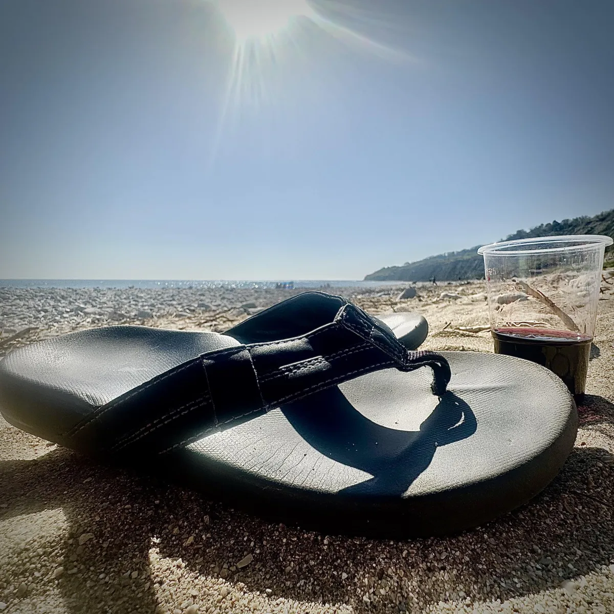 Flip flop and wine on a secret hidden beach Lyme Regis Dorset