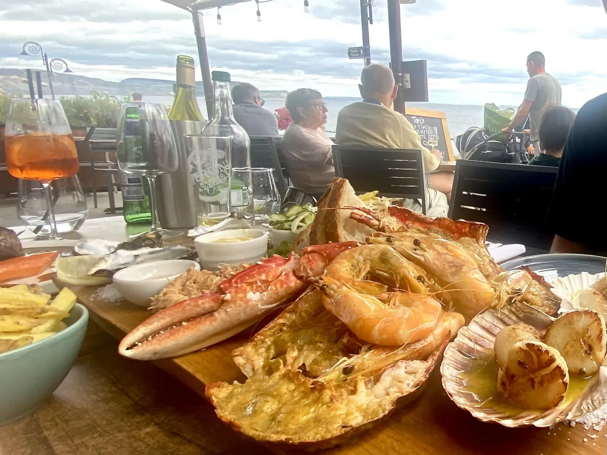 View of a traditional Dorset pub in Lyme Regis with outdoor seating overlooking the harbour, a popular spot for visitors searching for the best pubs in Lyme Regis to enjoy food and drink.