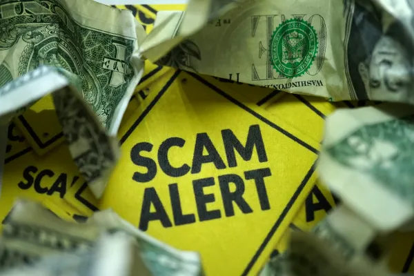 Scam alert sign surrounded by money, symbolizing financial risks of roofing contractor scams.