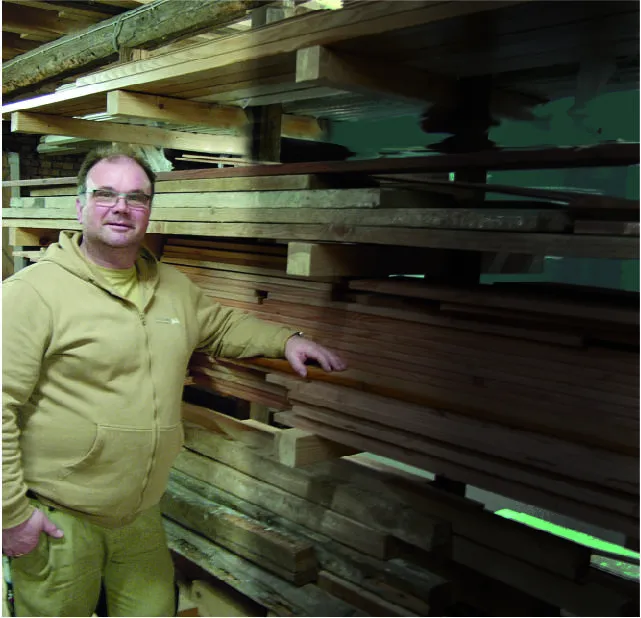 Handwerker in einer Tischlerei steht vor Holz