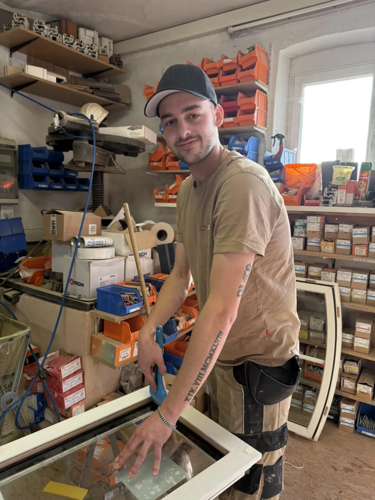 Handwerker in einer Tischlerei arbeitet mit Holz, umgeben von Werkzeugen und Materialien