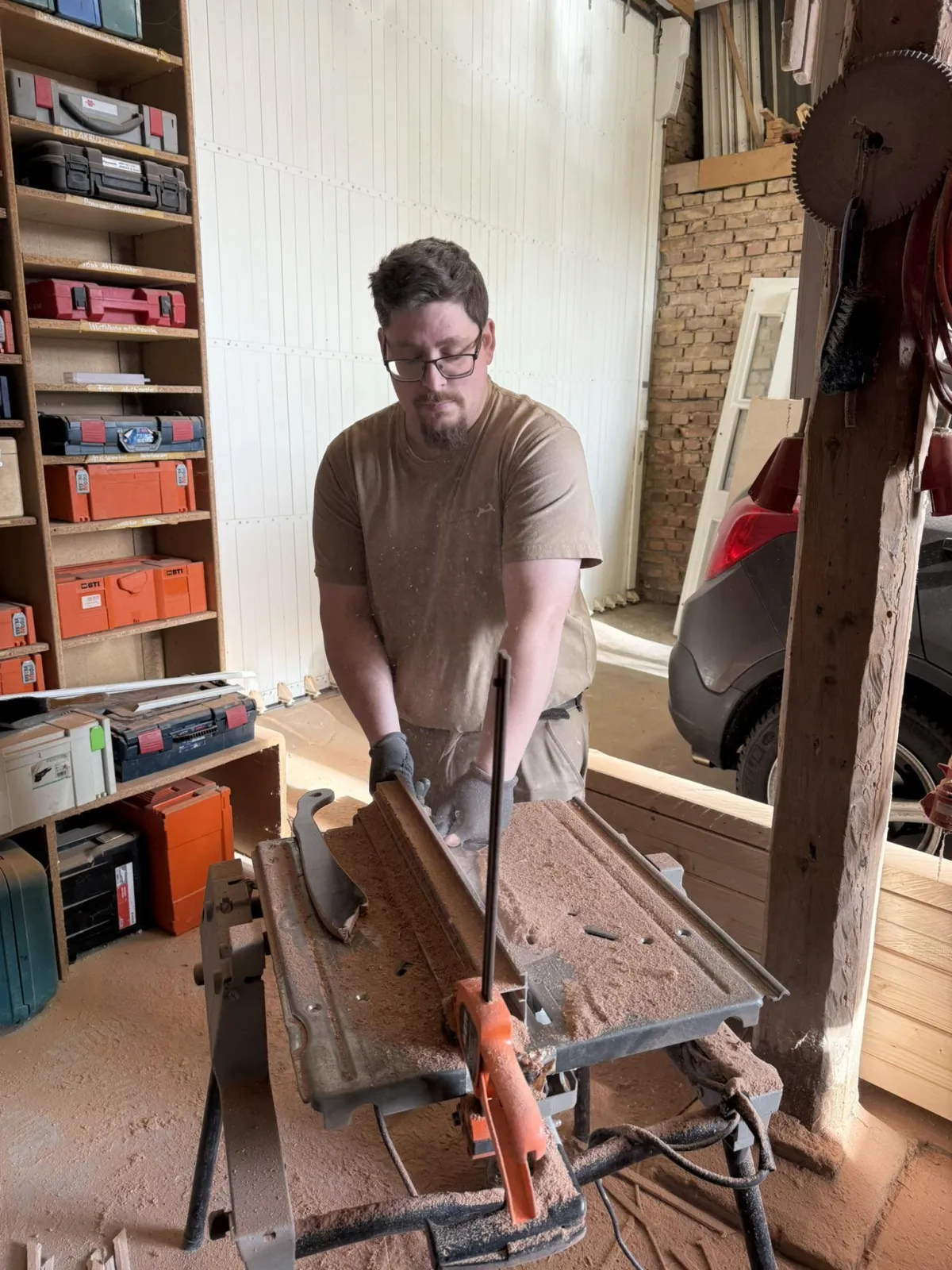 Handwerker in einer Tischlerei schneidet ein Holzstück mit einer Kreissäge, während er konzentriert arbeitet.
