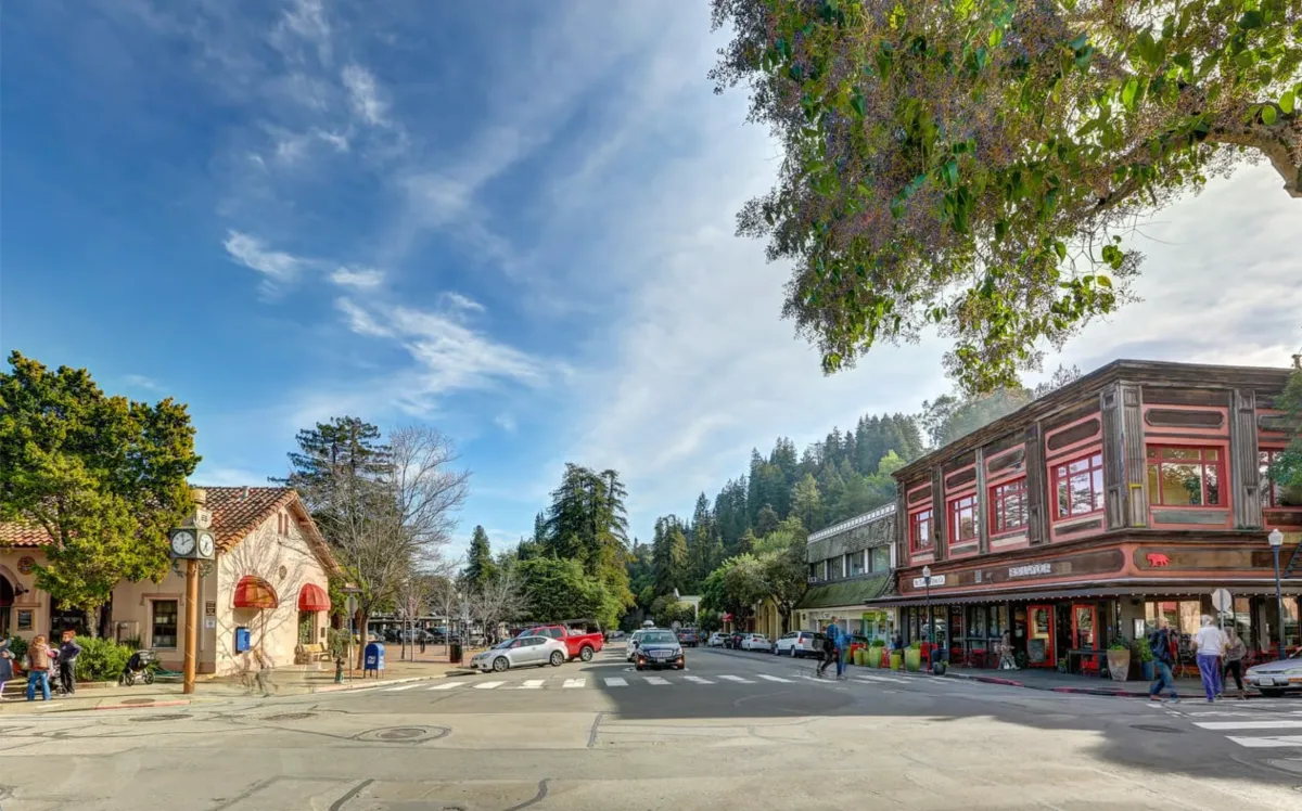A charming downtown Mill Valley street at golden hour, lined with shops and redwoods, capturing the inviting atmosphere of the First Tuesday ArtWalk.